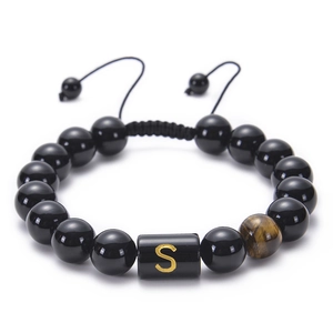 Detail of adjustable black onyx bead bracelet featuring gold letter S and tiger eye stone