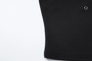 Detail shot of black ribbed fabric texture with a polished silver metal grommet eyelet