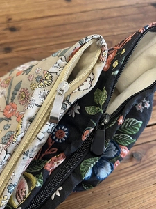 Detail of floral canvas makeup bags showing zippers and colorful flower patterns on fabric