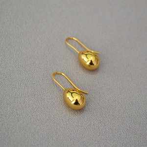 Macro shot of polished gold-plated teardrop earrings showing smooth reflective surface