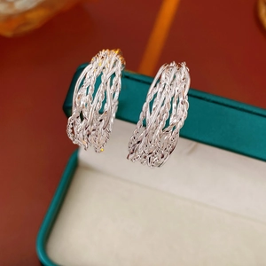 Detailed close-up of twisted rope texture on silver metal hoop earrings on a jewelry box