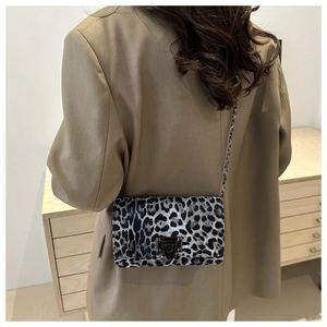 Woman wearing leopard print shoulder bag with chain strap over a khaki blazer