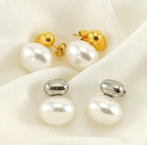 Detailed view of French vintage pearl stud earrings in gold and silver finish on fabric