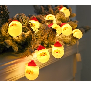 Close-up of Santa Claus LED string lights with warm yellow glow on a snowy Christmas tree