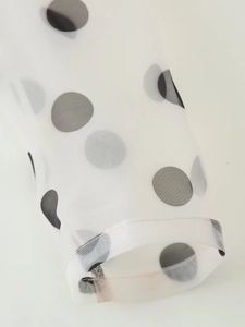Detailed macro view of white organza sleeve cuff with large black polka dot pattern