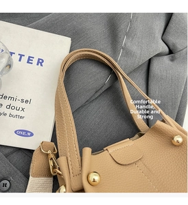Detail of lychee pattern leather bucket bag with gold circular buckle and wide fabric strap