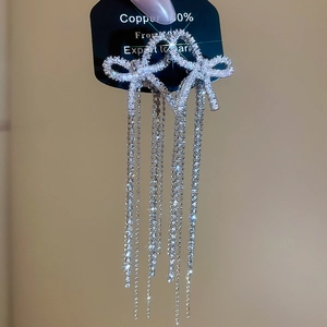 Detailed close-up of a silver bow earring with long tassels and sparkling cubic zirconia