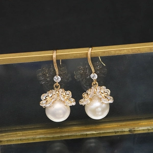 Macro detail of natural Edison pearl earrings with gold floral zircon accents