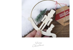Wooden Nutcracker soldier ornament in a gold metal ring with green pine tree detail