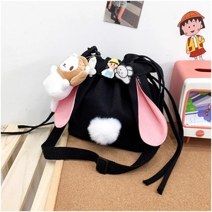 Close-up of black canvas bucket bag with pink rabbit ears and cute plush ball detail