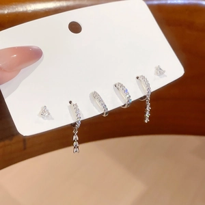 Detailed view of silver zircon earrings set with tassel charms on a white display card