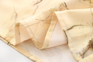 Vue macro du tissu beige avec imprimé végétal marron et couture d'ourlet délicate