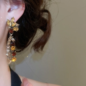 Detail view of French style floral tassel earrings with yellow and brown gemstones