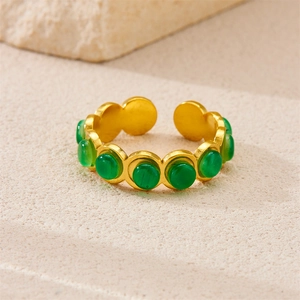 Detail of vintage 18k gold plated stainless steel ring with green stone on sandstone