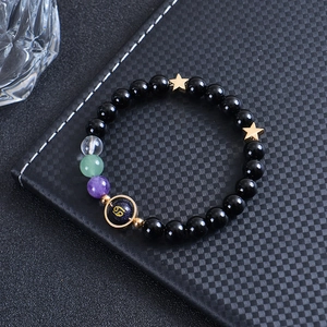 Macro shot of Cancer zodiac sign bead on black obsidian beaded bracelet with gold stars