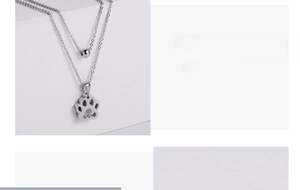 Detailed view of silver layered necklaces with bead and hollow dog paw print pendants