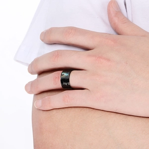 Macro detail of wide black stainless steel ring with hammered texture and shell inlay