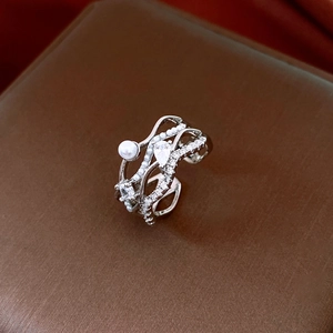 Gros plan sur une bague argentée multicouche ornée d'un cristal goutte et d'une perle