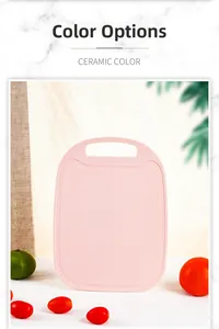Pink non-slip cutting board for fruits with hanging handle on marble kitchen tabletop