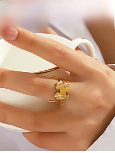 Close-up of golden leaf ring with detailed feather texture held by a model