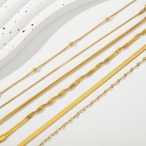 Detail view of five assorted 18K gold plated stainless steel chain bracelets on white wave