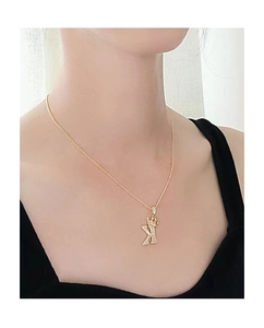 Dettaglio della collana dorata con corona e lettera K e zirconi indossata sul collo