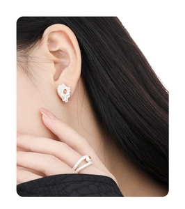 Detail view of irregular silver earrings and ring with orange gems on female model