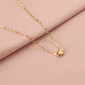 Detailed view of a gold shell pendant necklace on elegant pink fabric background