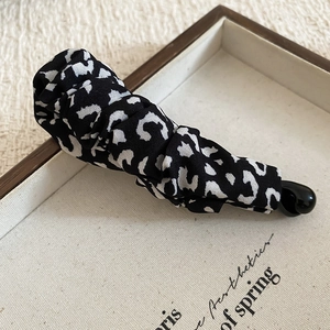Detail of leopard print fabric hair clip with pleated texture on a linen tray