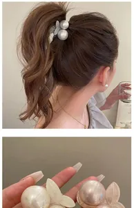 Close-up of elegant pearl hair clip with acrylic leaves on soft brown wavy hair