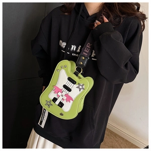 Detailed macro of a green guitar-shaped crossbody bag featuring star patches and wing charm