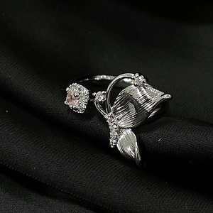 Macro shot of silver butterfly ring with pink gemstones on dark textured background
