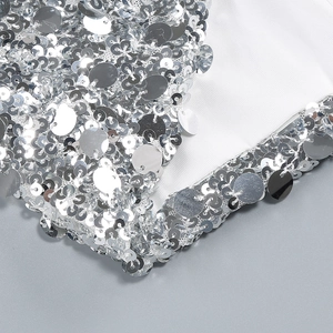 Detail shot of shimmering silver sequins sewn on premium white fabric dress material