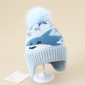 Detail of light blue baby knit earflap hat with shark pattern and large faux fur pom-pom
