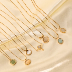 Gold necklace with opal and pearl charms on champagne silk background in diagonal layout