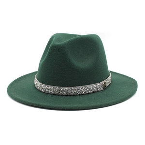 Detail of dark green fedora hat featuring sparkling rhinestone band and golden M buckle