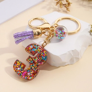 Detail of resin number 3 keychain with colorful glitter, purple tassel and golden metal parts