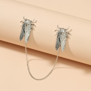 Detailed view of silver cicada pin brooch with link chain on a minimalist beige background