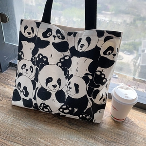 Detail of cute panda canvas tote bag with black strap handle on wooden windowsill