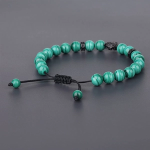 Macro detail of malachite beaded bracelet featuring a black leopard head and woven cord