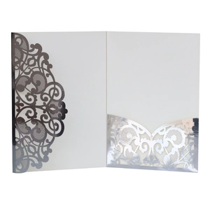 Detailed view of white laser-cut wedding invitation featuring intricate silver floral patterns