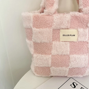 Close-up of pink and white checkered plush tote bag with embroidered logo lettering