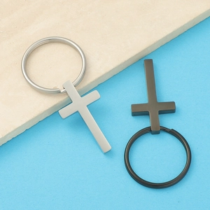 Close-up of modern silver and black stainless steel cross keychains on a textured surface