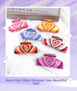 Flat lay of colorful acrylic heart hair claws in six vibrant patterns on white fabric