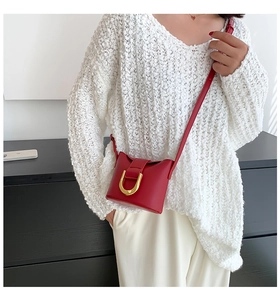 Detail shot of a red leather mini bucket bag with a gold U-shaped metal buckle buckle detail