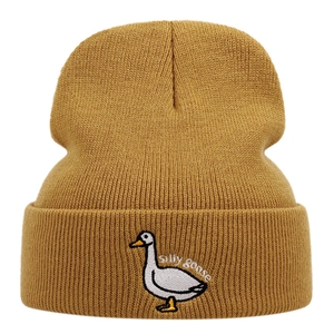 Detailed embroidery of a white goose and Silly Goose text on mustard yellow knit beanie