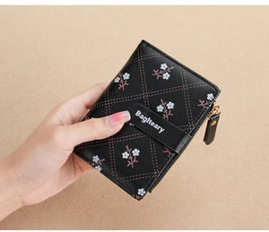 Detail of black PU leather wallet with quilted floral pattern and logo snap strap