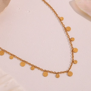 Detailed macro of 18K gold plated necklace with textured circular charms and water drops