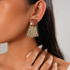 Close-up of geometric earrings with brown squares and green houndstooth fabric drops