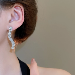 Close-up of sparkling silver wave drop earrings with pavé rhinestones on model